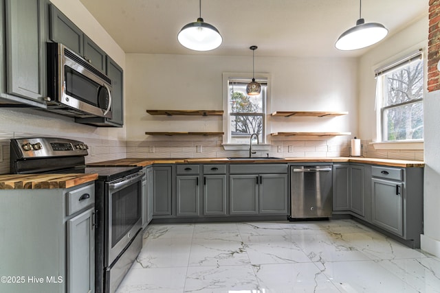 kitchen featuring butcher block countertops, appliances with stainless steel finishes, marble finish floor, open shelves, and a sink