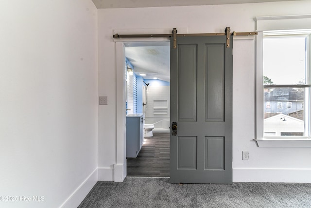 hall featuring dark colored carpet and baseboards