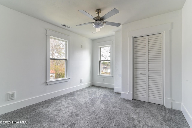 unfurnished bedroom featuring baseboards, visible vents, ceiling fan, carpet floors, and a closet