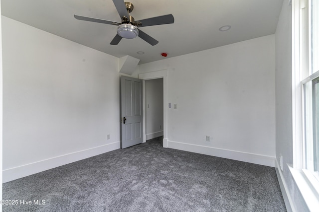 empty room with plenty of natural light, dark carpet, and baseboards