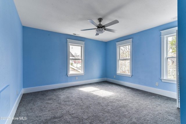 spare room featuring baseboards, plenty of natural light, visible vents, and carpet flooring