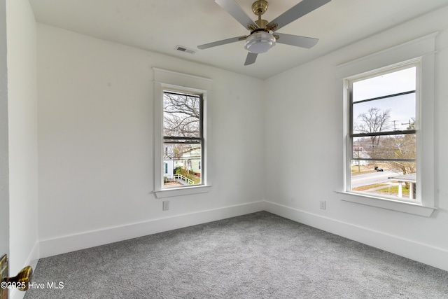 carpeted empty room featuring a healthy amount of sunlight, baseboards, visible vents, and ceiling fan