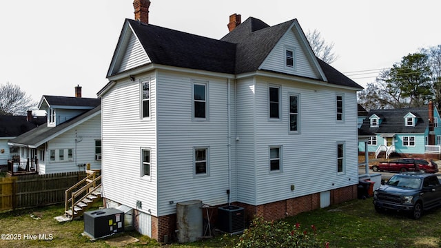 back of property with a yard, central AC, and fence