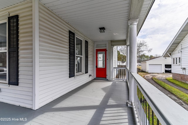 wooden deck with covered porch, a detached garage, and an outdoor structure