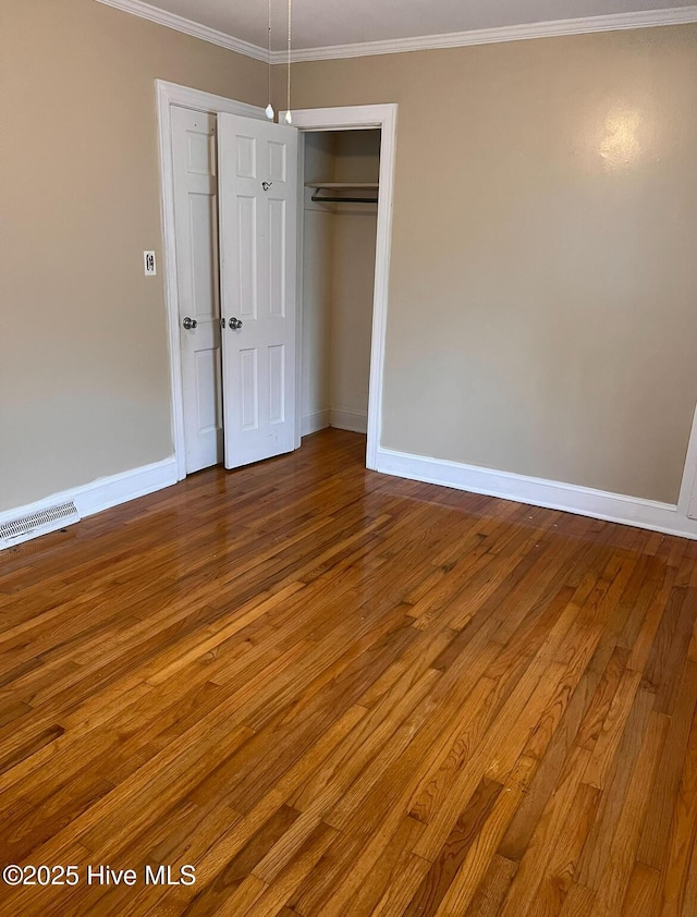 unfurnished bedroom featuring visible vents, crown molding, and wood finished floors