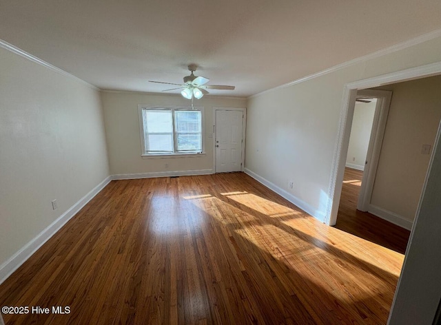 spare room with baseboards, wood finished floors, and crown molding