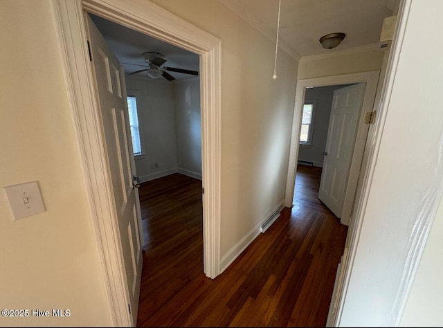 corridor featuring dark wood-style floors, visible vents, ornamental molding, attic access, and baseboards