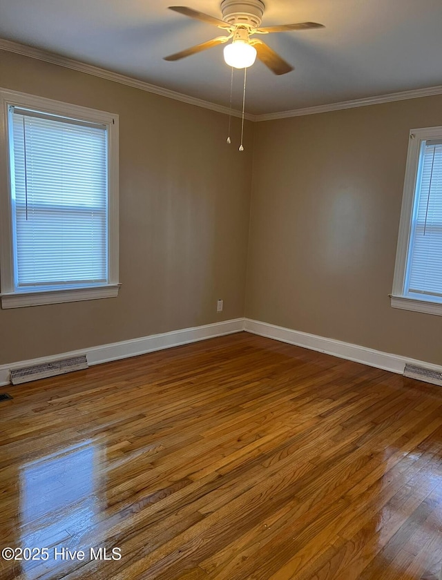 spare room featuring baseboards, crown molding, visible vents, and hardwood / wood-style floors