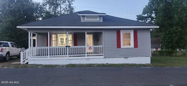 bungalow-style home with crawl space, covered porch, and roof with shingles