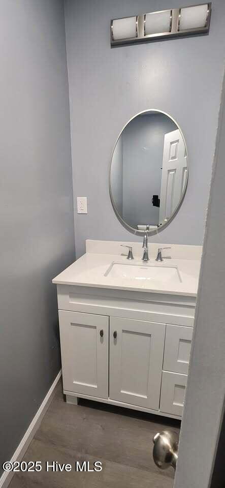 bathroom featuring wood finished floors, vanity, and baseboards