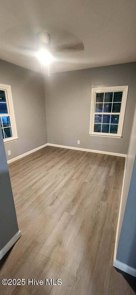unfurnished room with baseboards and wood finished floors