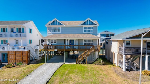 coastal inspired home with covered porch, stairway, board and batten siding, and a front lawn