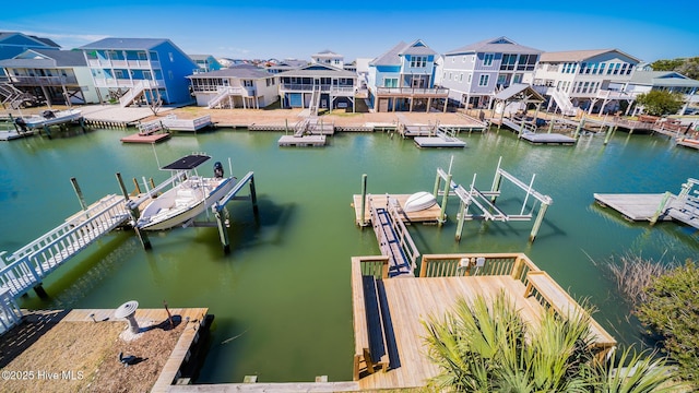 dock area featuring a water view, boat lift, and a residential view