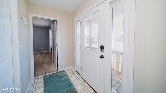 doorway to outside with light floors, light carpet, and baseboards