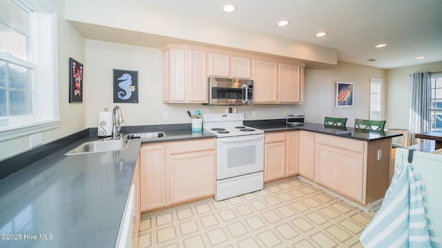 kitchen featuring electric range, dark countertops, stainless steel microwave, a peninsula, and light floors