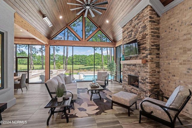 interior space with ceiling fan, high vaulted ceiling, a stone fireplace, wood ceiling, and floor to ceiling windows