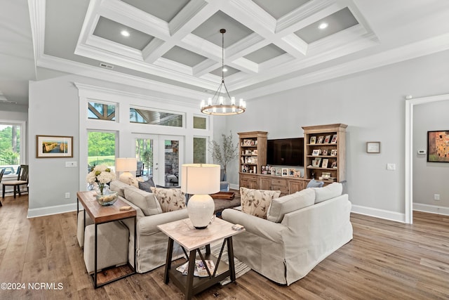 living area featuring french doors, a towering ceiling, an inviting chandelier, ornamental molding, and wood finished floors