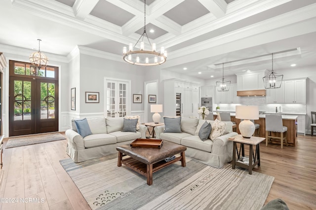 living area featuring french doors, beamed ceiling, light wood-style floors, and a notable chandelier