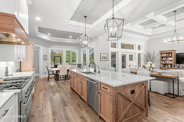 kitchen with stainless steel dishwasher, a notable chandelier, light wood finished floors, and a sink