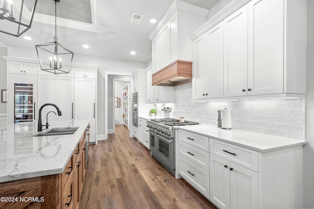 kitchen featuring stainless steel appliances, visible vents, backsplash, a sink, and wood finished floors