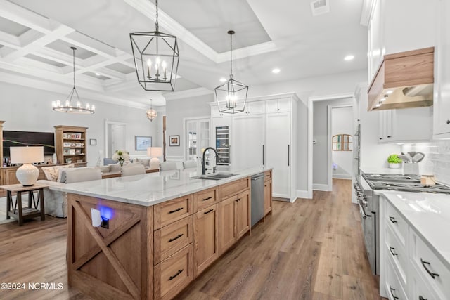 kitchen with appliances with stainless steel finishes, light wood-type flooring, a sink, and ornamental molding