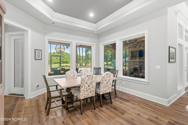 dining room with a tray ceiling, crown molding, recessed lighting, wood finished floors, and baseboards