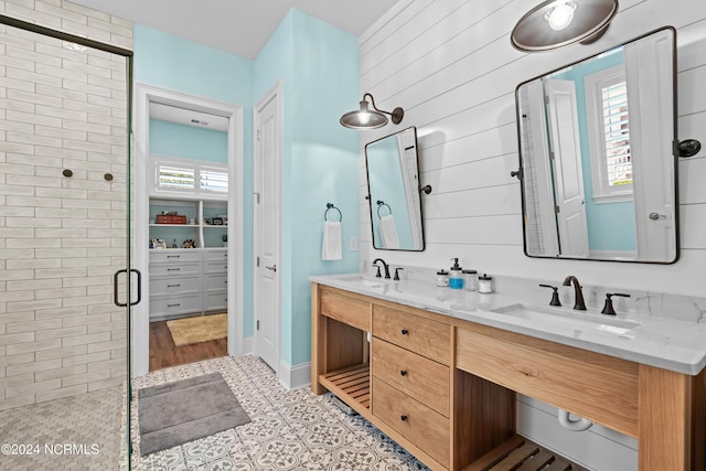 bathroom with a closet, double vanity, a stall shower, and a sink