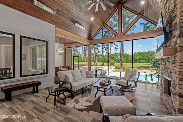 sunroom / solarium with ceiling fan with notable chandelier, vaulted ceiling, a fireplace, and wood ceiling