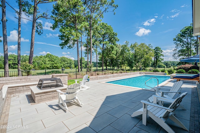 view of pool with a patio, fence, and a pool with connected hot tub