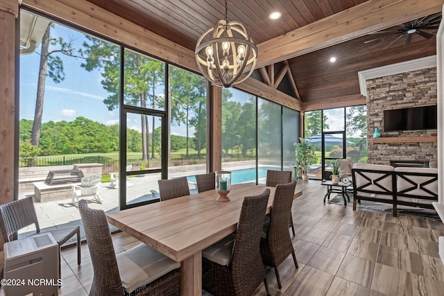 sunroom / solarium with wood ceiling, a fireplace, lofted ceiling with beams, and ceiling fan with notable chandelier