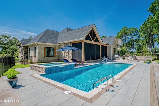 view of swimming pool with a sunroom, a pool with connected hot tub, a patio, and fence