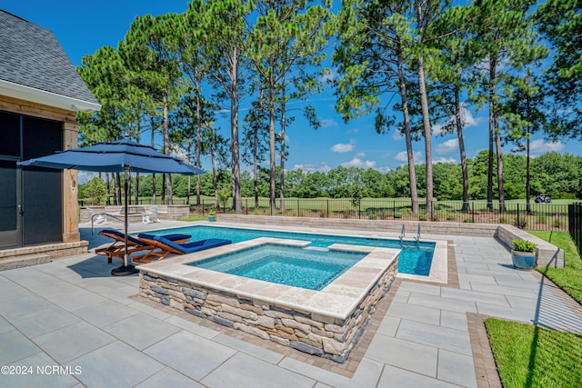 view of swimming pool with a pool with connected hot tub, a patio area, and a fenced backyard