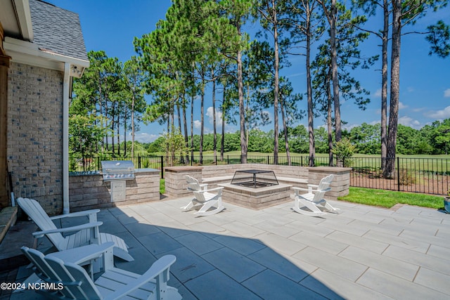 view of patio / terrace featuring an outdoor fire pit, fence, an outdoor kitchen, and area for grilling