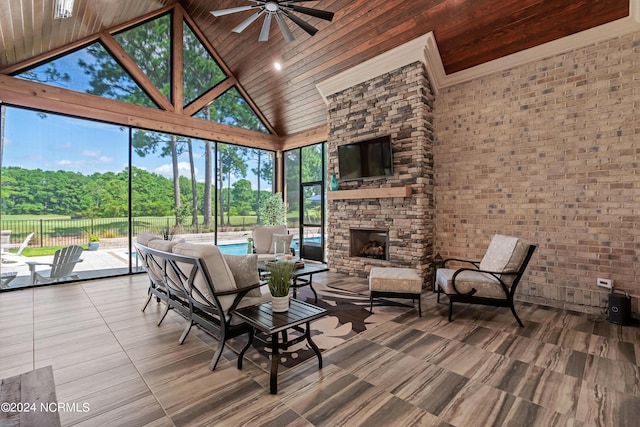 unfurnished sunroom with a ceiling fan, wood ceiling, vaulted ceiling, and a stone fireplace