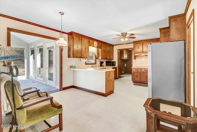 kitchen featuring a peninsula, light floors, brown cabinets, and light countertops