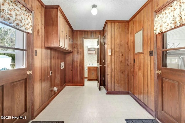 interior space featuring electric panel, wood walls, a textured ceiling, and light floors