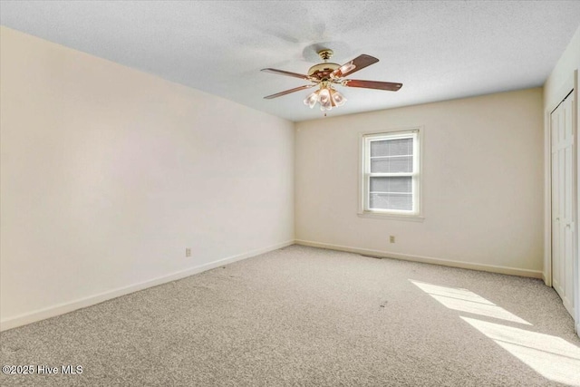 unfurnished room with light carpet, ceiling fan, a textured ceiling, and baseboards