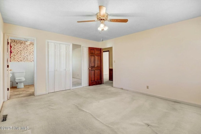 unfurnished bedroom with carpet, multiple closets, visible vents, ensuite bath, and baseboards