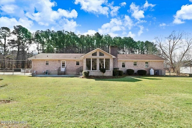 rear view of house with brick siding, fence, a yard, a chimney, and a patio area