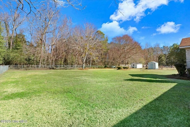 view of yard with a storage shed, an outdoor structure, and fence