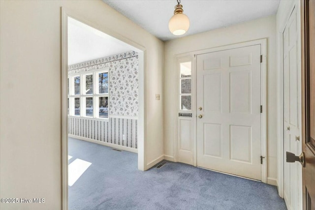foyer entrance with baseboards, carpet, and wallpapered walls