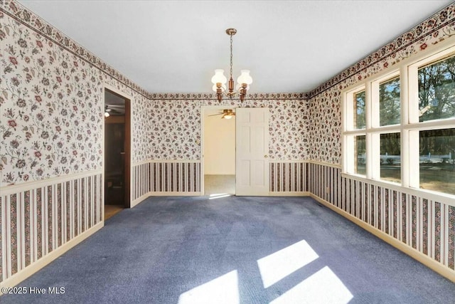 empty room with carpet floors, an inviting chandelier, and wallpapered walls