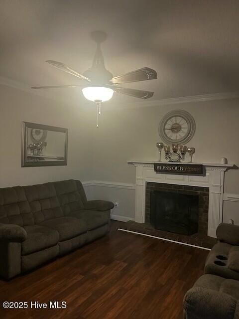 living area with ornamental molding, a ceiling fan, a fireplace, and dark wood-style floors