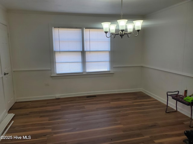 unfurnished dining area with baseboards, ornamental molding, dark wood finished floors, and a notable chandelier