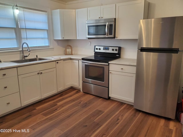 kitchen with stainless steel appliances, dark wood-style flooring, white cabinets, and a sink