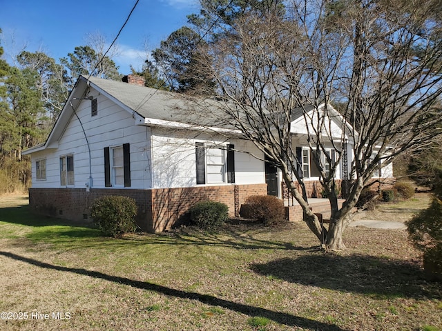 view of side of home featuring crawl space, brick siding, a yard, and a chimney