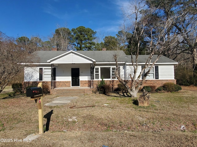 ranch-style house featuring covered porch, a front yard, and brick siding