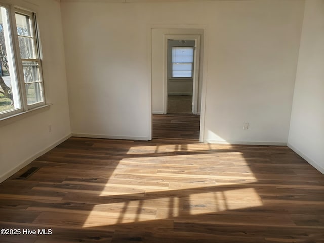 empty room featuring visible vents, baseboards, and wood finished floors