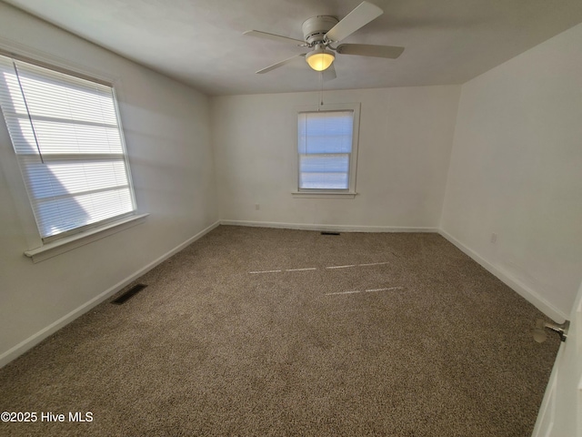 unfurnished room with carpet floors, visible vents, ceiling fan, and baseboards