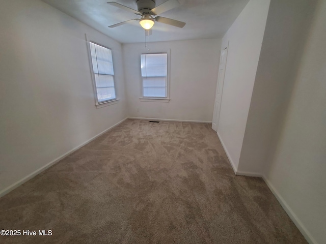 carpeted spare room with a ceiling fan and baseboards